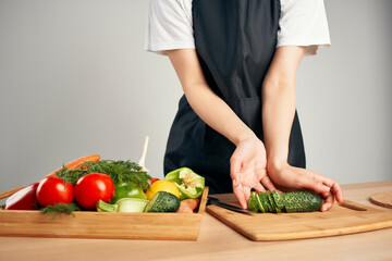 Woman in black apron cutting vegetables in the kitchen housewife preparing food