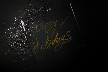 Happy Holidays. Beautiful sparkling Golden Happy Holidays on a black background for a design With Space For Copying Text. A beautiful glowing overlay template for a festive greeting card.