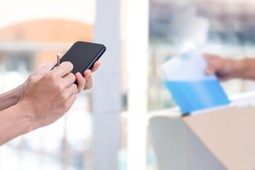 Women use electronic pen Sign and check list on smartphone after check pick up Alcohols ethanol spray from the post office transport stay at home concept