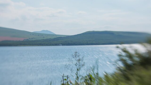 Timelapse on the shore of Lake Tambukan. The movement of clouds and water. The sun's glare is reflected. Taken on the "lens baby" with the effect titl shift