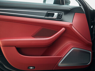 Control panel with chrome handle on the car door red genuine leather in a new car with arm rest with seat setting.