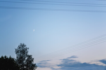 Fototapeta premium evening clear sky with a moon between the electrical wires, with clouds below