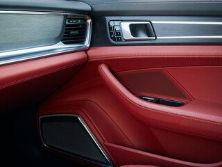 Control panel with chrome handle on the car door red genuine leather in a new car with arm rest with seat setting.