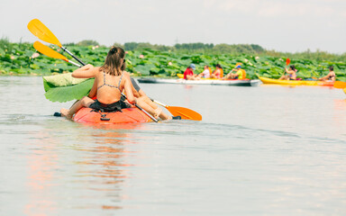 people paddling a kayak in the lagoon between lotus flower in river. Kayaking in Mincio river, Italy