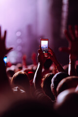 Using a smartphone in a public event,  live music festival.  Holding a mobile phone in hands and...