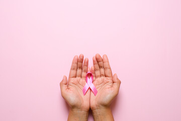 Hands holding pink ribbon, breast cancer awareness, October pink concept