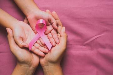 Woman hands holding pink ribbon, breast cancer awareness, October pink concept