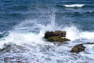 Splashing wave crashes against a large rock