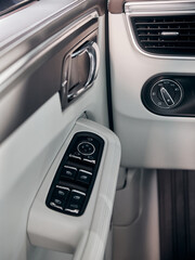 Car white leather interior detail. Windows control buttons and door handle.