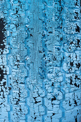 Vertical photograph of the surface of an old car tire painted blue peeling off