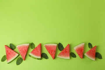 Juicy watermelon slices and leaves on green background