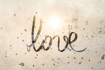 winter glass with sun, inscription love on frozen glass, Valentine's Day card