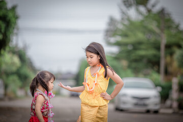 Close-up background view of a blurred Asian girl running or teasing in the street in front of the house, doing activities together outside the classroom during the holidays.