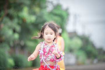 Naklejka premium Close-up background view of a blurred Asian girl running or teasing in the street in front of the house, doing activities together outside the classroom during the holidays.