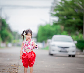Close-up background view of a blurred Asian girl running or teasing in the street in front of the...