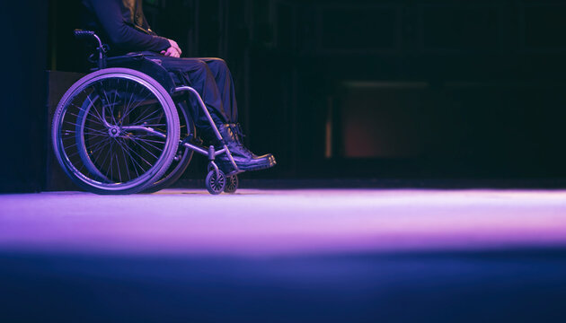 A man in a wheelchair on a dark background, without a face. Conceptual image of handicapped and disabled people banner format.