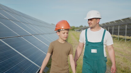 Engineer father is explaining to his little son an operation and performance of photovoltaic solar panels. Concept of Ecological Renewable Energy and Quality Family Time. Concept: renewable energy