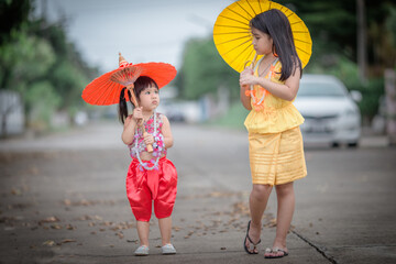 Close-up background view of two young Asian girls running or teasing in blur on the street in front...