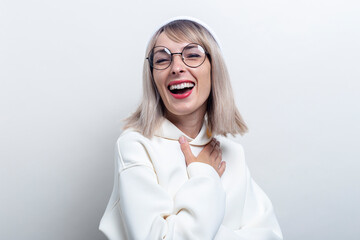 Cheerful young girl in glasses in a hoodie on a light background