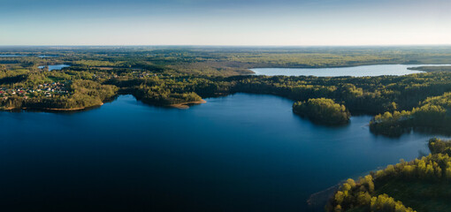 Obraz premium Aerial drone photo of green tree crones growing in lake shore. Nature landscape. Top view of a forest lake. Travel concept.