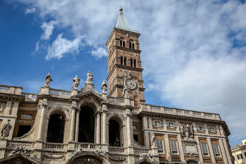 Fototapeta na wymiar The bell tower of The Basilica of Saint Mary Major (Italian: Basilica di Santa Maria Maggiore) in Rome, against the background of a blue cloudy sky