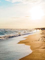 sandy seashore, foamy waves at sunset - beautiful landscape