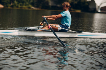 Sportsman single scull man rower rowing on boat.