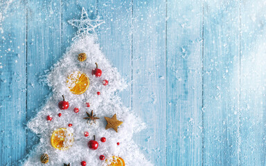 Creative christmas background. Christmas tree made of snow with handmade natural decorations on a blue wooden board flat lay. - Powered by Adobe