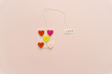 Lovely arrangement of colorful hearts and tea bag on pink back ground.