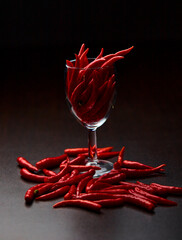 the red chili peppers in glass cup with place on table isolated on black