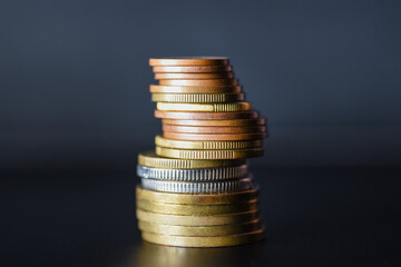 Tower of metal coins on black background