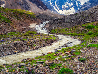 Winding mountain river among rocks and snow on an autumn high-altitude plateau.