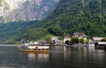Fototapeta na wymiar Boat sailing in the lake of Hallstatt, with the Alpine mountains behind it.