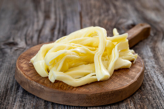 Chechil cheese or string cheese on wood floor. Cheese on serving board