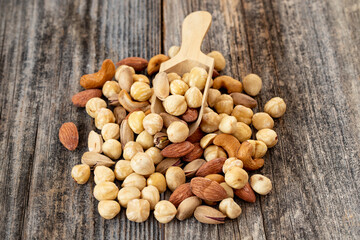 Mixed nuts on wood floor. Organic and fresh nuts. Wooden spoon on top of nuts. close up