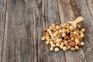 Mixed nuts on wood floor. Organic and fresh nuts. Wooden spoon on top of nuts. copy space