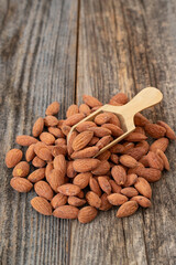Almond nuts on wood background. Organic and fresh nuts. Wooden spoon on pile of almonds. close up