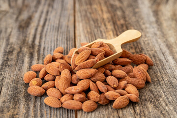 Almond nuts on wood background. Organic and fresh nuts. Wooden spoon on pile of almonds. close up