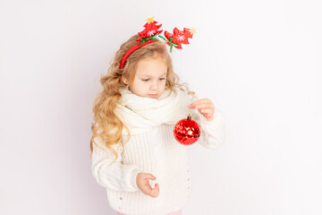 baby girl holding a red Christmas ball on a white isolated background, space for text