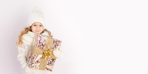 baby girl holding gift in warm hat and sweater on white isolated background, place for text, banner