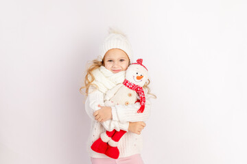 baby girl with snowman toy in warm hat and sweater on white isolated background, place for text