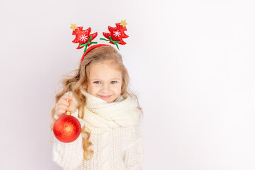 baby girl holding a red Christmas ball on a white isolated background, space for text