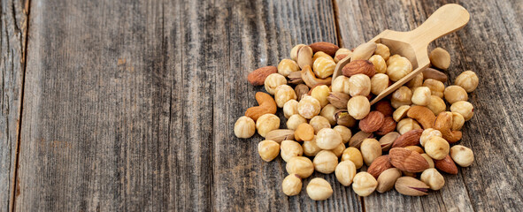 Mixed nuts on wood floor. Organic and fresh nuts. Wooden spoon on top of nuts. Copy space