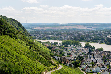 Fototapeta na wymiar The Rhine River flowing between the grape hills, the village buildings are visible, aerial view.