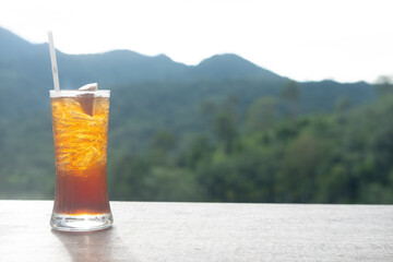 Iced lemon tea in long glass on the green nature background