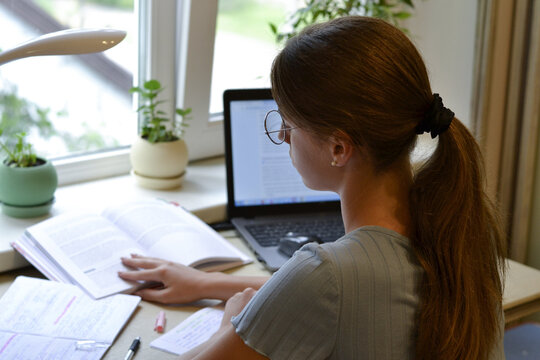 girl student studying at home with books and laptop