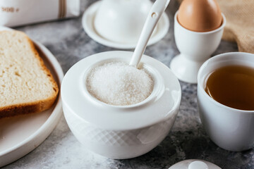white sugar in a ceramic bowl on a marble background