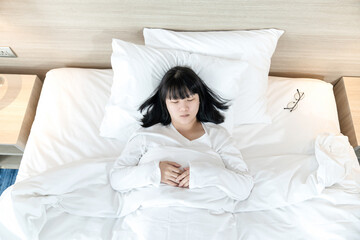 Asian woman sleeps on white bed after exhausted and tried all day.