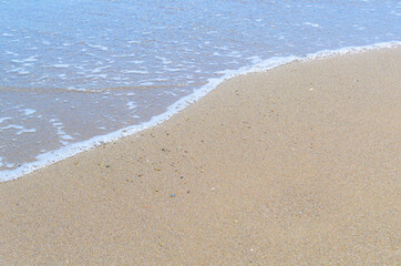 Fototapeta na wymiar Texture of sand with an edge of sea-wave foam.