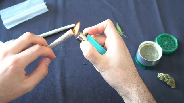 First person view of a man lighting up a joint of cannabis at home.